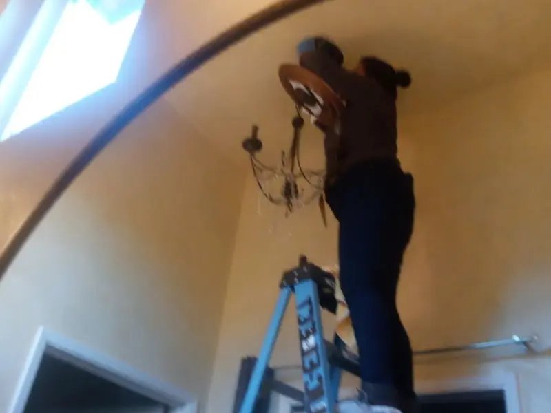 Electrician installing a chandelier in a Hickman residence